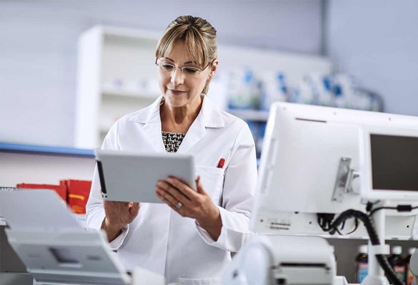 Farmacevtka v beli uniformi uporablja tablico