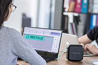 Ženska z očali oblikuje nalepke na P-touch Cube Plus prek računalnika